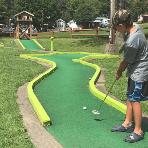 A boy is playing miniature golf in a park located in Western New York.