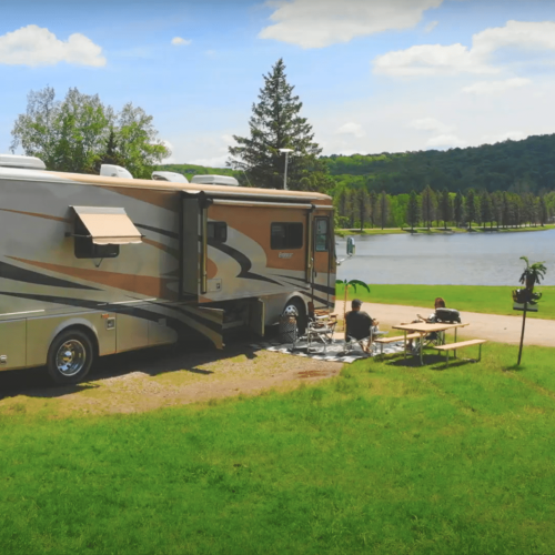 A Rainbow Lake campground with an RV parked near a grassy area.